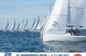 Mehrere Segelboote bei einer Regatta auf dem Wasser, alle mit weißen Segeln, die in eine Richtung fahren, unter einem teilweise bewölkten Himmel, mit einigen Teilnehmern sichtbar an Bord der Boote.